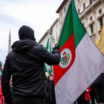 ALT: Corteo a Milano per la Palestina con scritta provocatoria "spara a Giorgia" e danni visibili.
